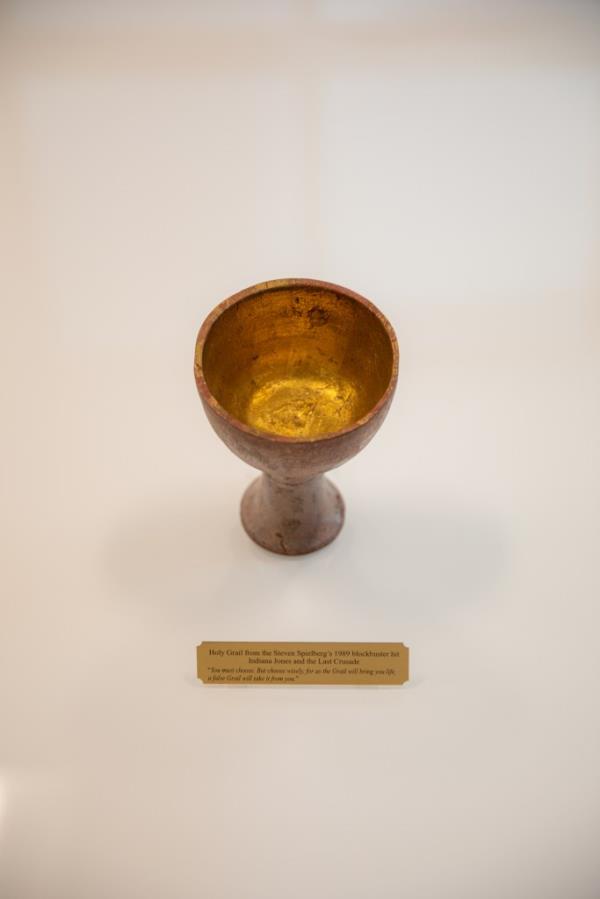 A photo of a gold Holy Grail cup on a white surface.