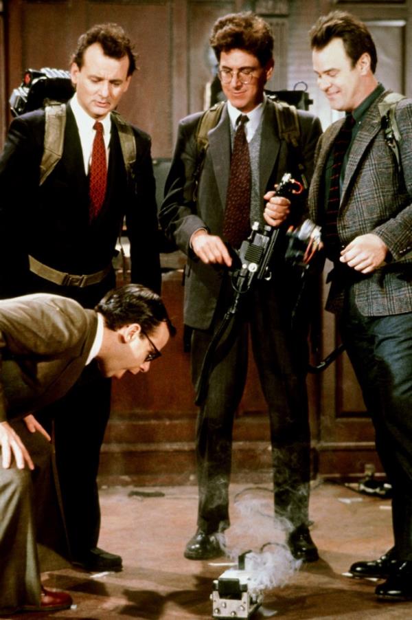 Rick Moranis, Bill Murray, Harold Ramis, and Dan Aykroyd in suits standing together in a scene from Ghostbusters II.