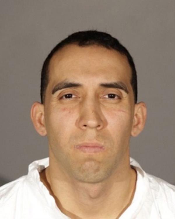 a man in a white shirt standing against a wall - Abraham Pablo Herrera Mo<em></em>ntecino - AKA Juan Eduardo Salomon Castro