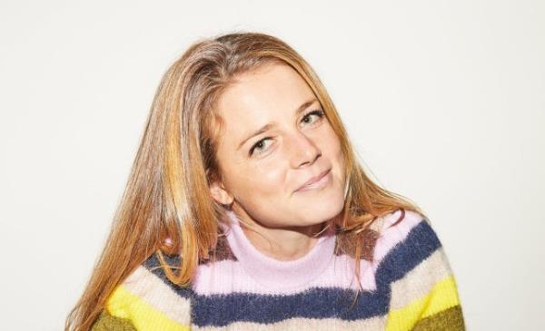 Pandora wearing a striped jumper, her head tilted, looking to camera and smiling