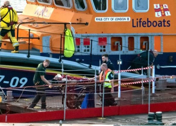 TOPSHOT - Paramedics assist a migrant picked up at sea while attempting to cross the English Channel, after they were picked up by a UK Royal Natio<em></em>nal Lifeboat Institution (RNLI) lifeboat and brought to the Marina in Dover, southeast England, on August 12, 2023. Six Afghan males died when a migrant boat heading to Britain sank in the Channel early Saturday, French officials said, as a search co<em></em>ntinued to find those still missing. (Photo by Stuart Brock / AFP) / RESTRICTED TO EDITORIAL USE (Photo by STUART BROCK/AFP via Getty Images)
