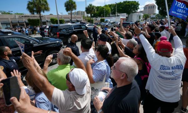 A crowd of people watching as Trump's motorcade departs the Cuban restaurant.