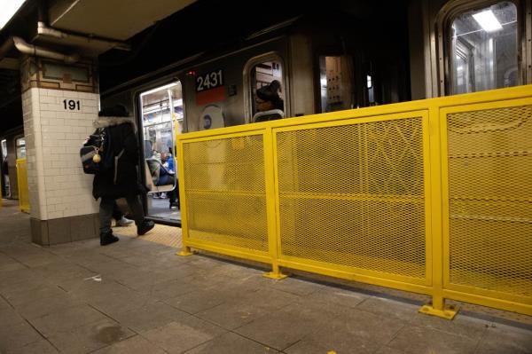 man waiting for train next to barriers installed to prevent people from falling o<em></em>nto train tracks at 191st St. in Manhattan