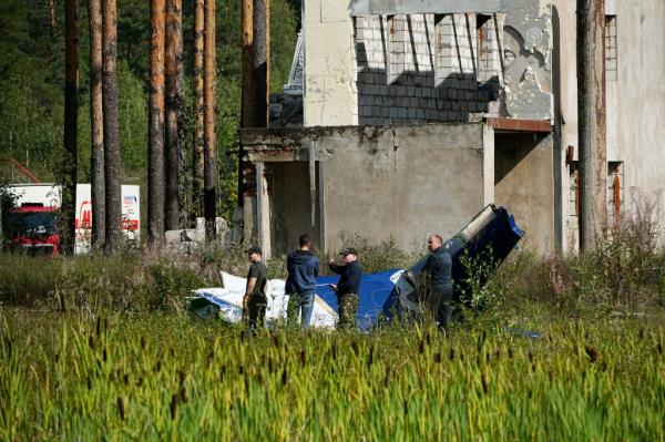 Russian servicemen inspect a part of a crashed private jet near the village of Kuzhenkino, Tver region, Russia, Thursday, Aug. 24, 2023
