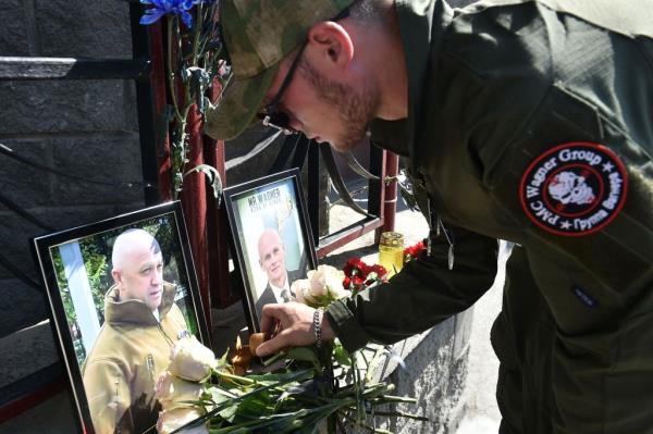 A member of private mercenary group Wagner pays tribute to Yevgeny Prigozhin (L) and Dmitry Utkin, a shadowy figure who managed Wagner's operations and allegedly served in Russian military intelligence, at the makeshift memorial in front of the PMC Wagner office in Novosibirsk, on Thursday.