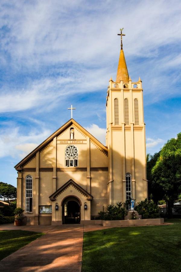 A scenic view of a small church on Maui in the tourist town of Lahaina call Maria Lanakila on a beautiful late afternoon right before sunset as the low sun casts shadows on the church.