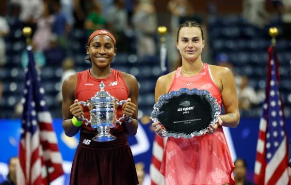 Coco Gauff holds up the trophy and poses with Aryna Sabalenka