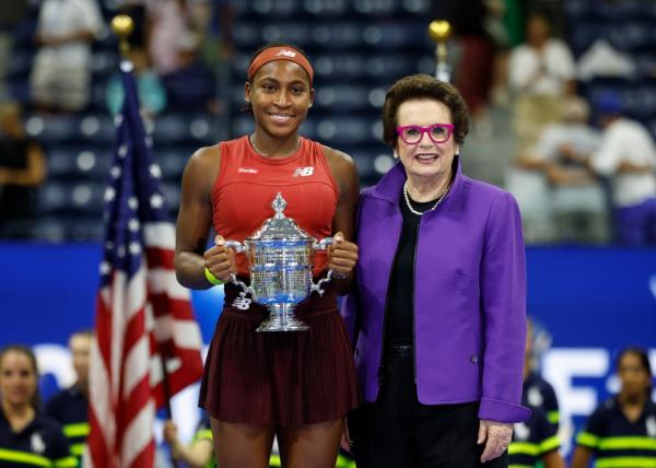 Coco Gauff holds up the trophy and poses with Billie Jean King 