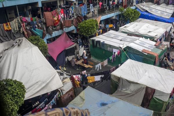 A general view shows internally displaced Palestinians sitting near shelters at a United Nations school courtyard, in Deir Al Balah town, southern Gaza Strip