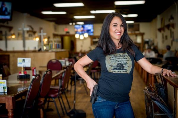Rep Lauren Boebert holds a handgun as she poses inside a bar 