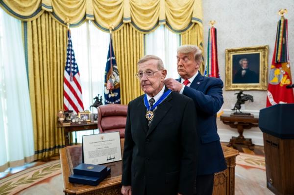  President Do<em></em>nald Trump presents the Medal of Freedom to former college football coach Lou Holtz in the Oval Office of the White House on December 3, 2020.