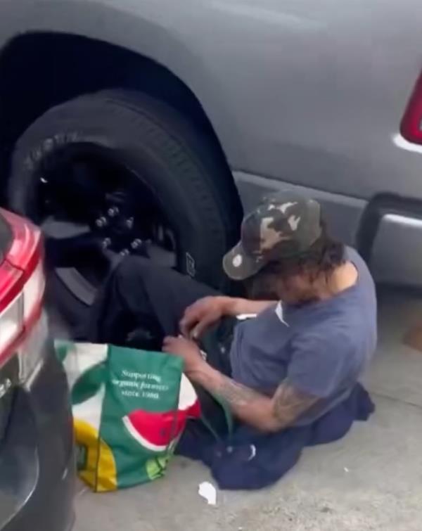Screenshot of a March 17 Instagram video of a man sitting between firefighter's cars parked on 3rd Avenue and pulling out what appears to be a needle