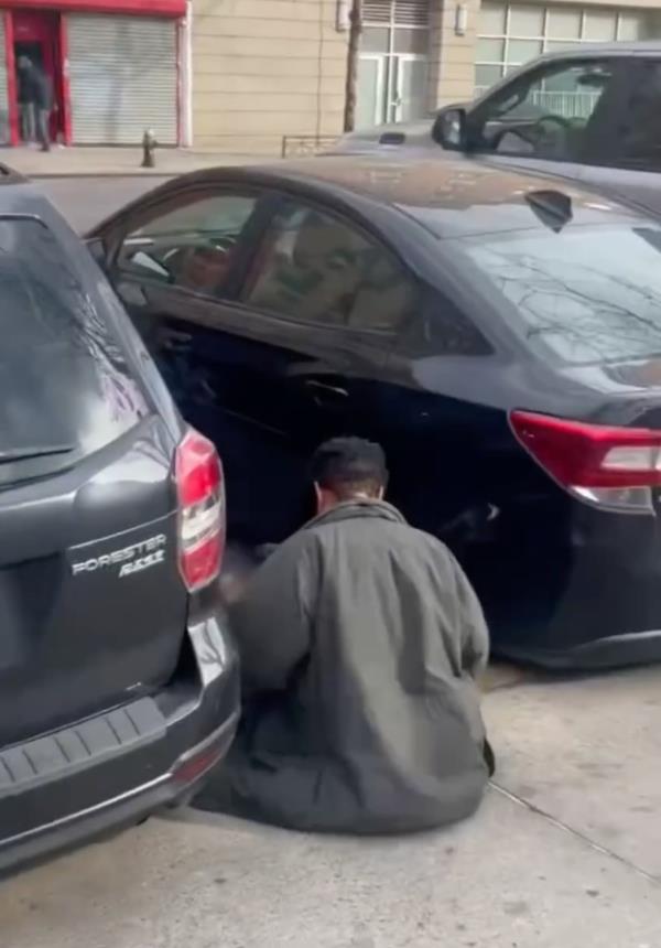 Screenshot of a March 17 Instagram video of a man sitting between firefighter's cars parked on 3rd Avenue