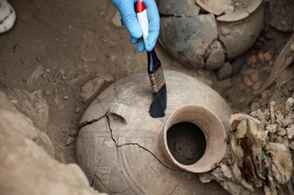 An archaeologist cleans the remains of a 1,000-year-old mummy