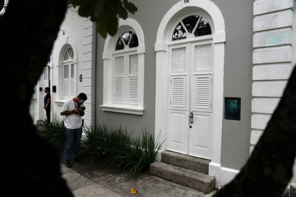 A tropical looking building with a news photographer in front