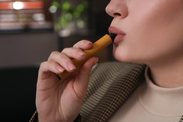 Young woman using disposable electro<em></em>nic cigarette 
