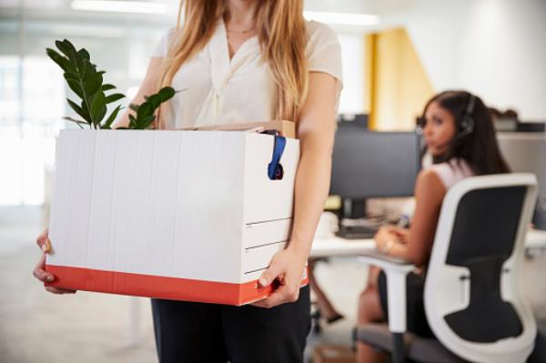 Fired female employee holding box of belo<em></em>ngings in an office