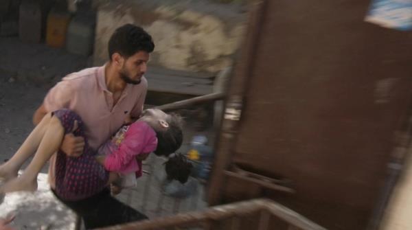 A Palestinian man carrying an injured child after a blast in Gaza City on October 18, 2023.