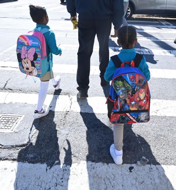 Students leaving school P.S. 160 in Queens, New York, adult seen with two children walking on a crosswalk