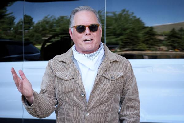 David Zaslav, CEO of Warner Bros. Discovery, speaking to the press upon arrival at the Sun Valley Media and Technology Conference, wearing sunglasses and a striped jacket