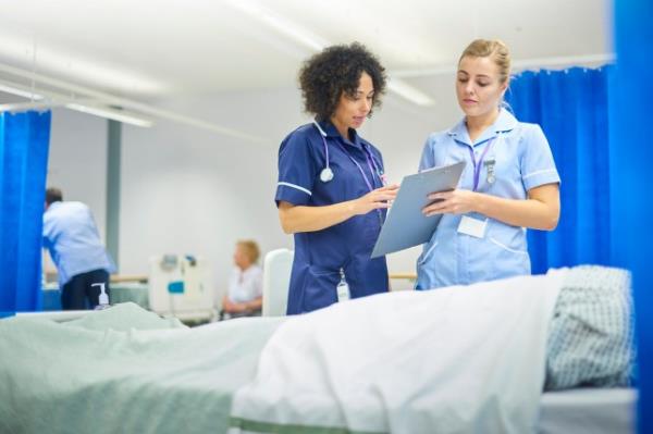 a senior staff nurse runs through some notes with young nurse on the ward