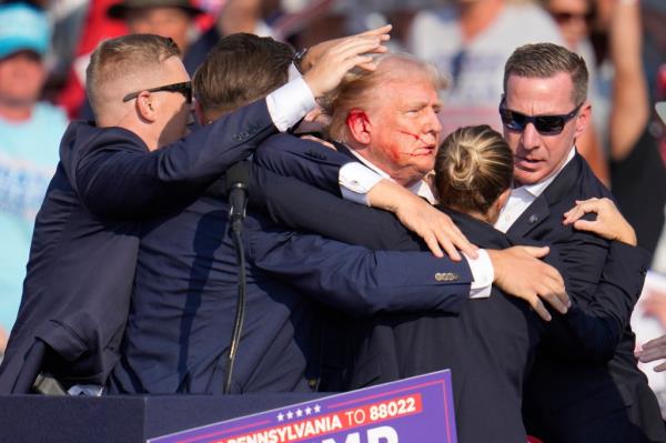 Former President Do<em></em>nald Trump surrounded by Secret Service agents at a 2024 campaign rally in Butler, Pa.