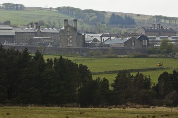 View of large stone building HMP Dartmoor prison with trees in the background, located in Princetown, Devon, UK
