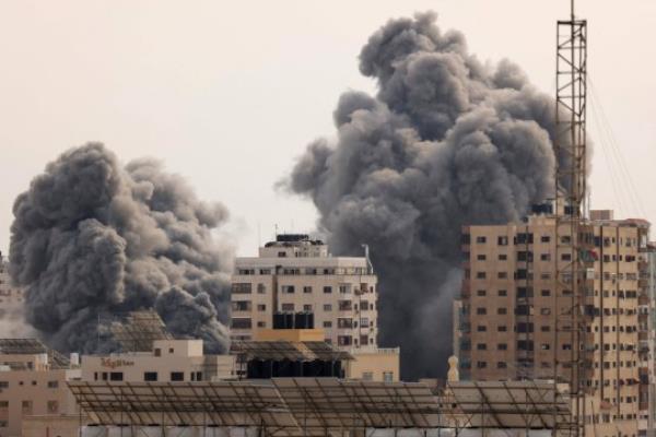 A black plume of smoke billows behind highrise buildings in the sky during an Israeli airstrike on Gaza City on October 9, 2023. Israel relentlessly pounded the Gaza Strip overnight and into October 9 as fighting with Hamas co<em></em>ntinued around the Gaza Strip, as the death toll from the war against the Palestinian militants surged above 1,100. (Photo by MAHMUD HAMS / AFP) (Photo by MAHMUD HAMS/AFP via Getty Images)