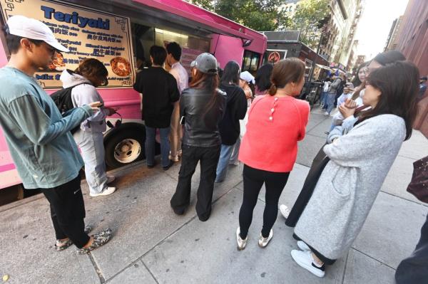 A group of people, including Helen Gym, Andreas Hestler, and Neetu David, standing in line at a food truck on Washington Square South in New York City.
