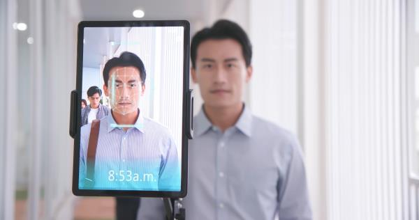 Asian businessman using face scanner to clock in work and check body temperature