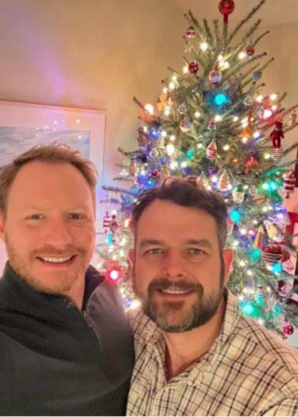 Christopher Kucera, 46, and Zachary Hatcher, 43, in front of a Christmas tree
