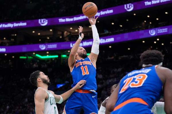 New York Knicks guard Jalen Brunson scoring a basket against Boston Celtics forward Jayson Tatum in a basketball game
