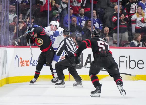 Morgan Rielly #44 of the Toro<em></em>nto Maple Leafs cross-checks Ridly Greig #71 of the Ottawa Senators in the head after his empty-net goal.