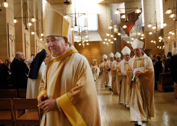 Coadjutor Archbishop Jose H. Gomez leaving after a welcoming Mass, marking the start of his ministry in Los Angeles, surrounded by men in robes