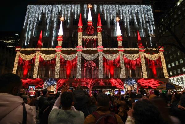 Crowd gathered at Rockefeller center to see light show on Saks Fifth Avenue store building 