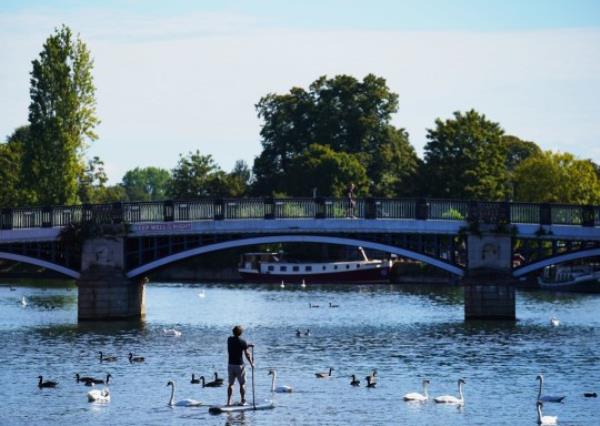 A paddle boarder travels along the River Thames near Windsor, Berkshire. A hot spell set to sweep the country on Wednesday could be the last this year, forecasters have said. The Met Office expects temperatures to peak in the late 20s in some areas before the mercury dips and the sunshine gives way to more unsettled co<em></em>nditions over the bank holiday. Picture date: Wednesday August 23, 2023. PA Photo. Photo credit should read: Jo<em></em>nathan Brady/PA Wire