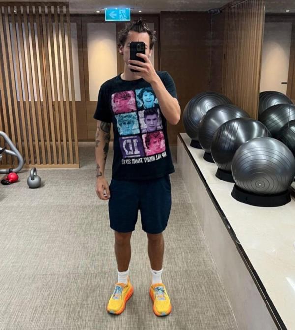 Harry Styles wearing Hoka sneakers, reflected in a mirror for a selfie