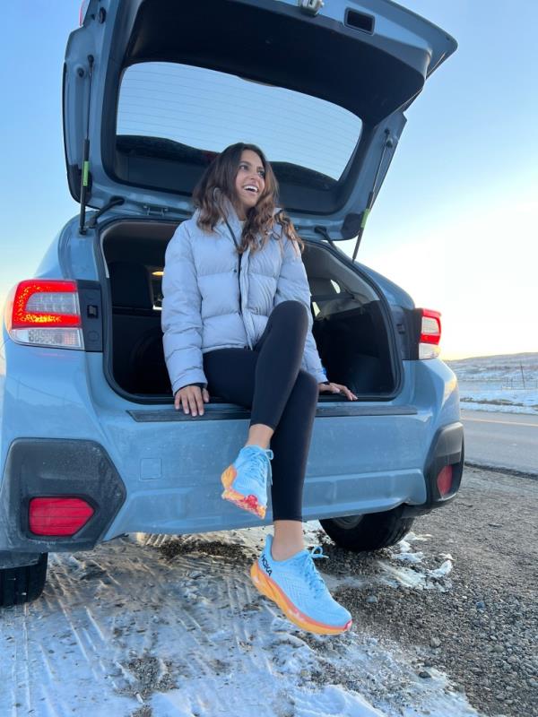 Reneé Noe, a runner, sitting in the back of a car for a Hoka Shoes lifestyle story