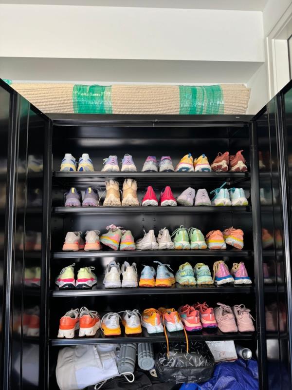 Runner Reneé Noe pictured with a black cabinet filled with many pairs of Hoka shoes