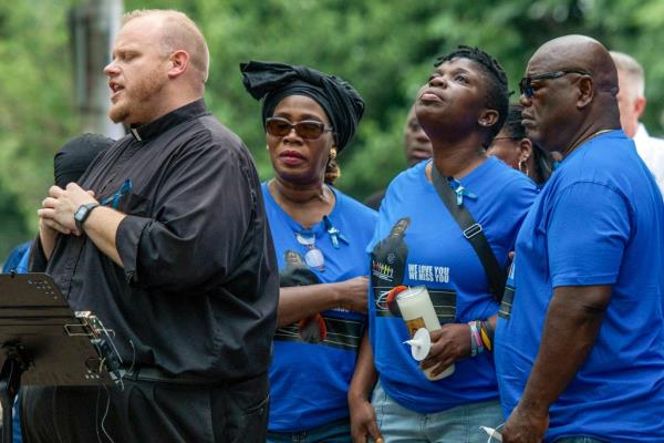 Jo<em></em>nathan Slavinskas, left, prays with the family of Harris Wolobah, including mother Lois and father Amos Wolobah, right, during a vigil in Newton Square Friday, Sept. 8, 2023
