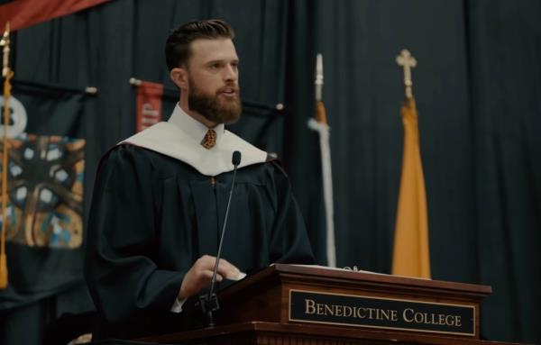 Harrison Butker, in academic robe, delivering critical commencement speech at Benedictine College
