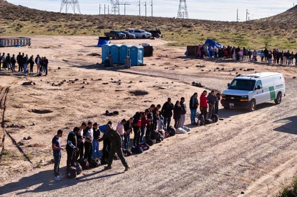 Dozens of migrants stand in lines at the San Diego border as border agents take them into custody.