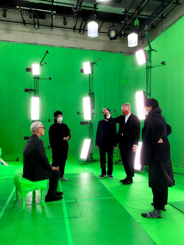 Ryuichi Sakamoto and a group of people in a greenscreened motion capture studio